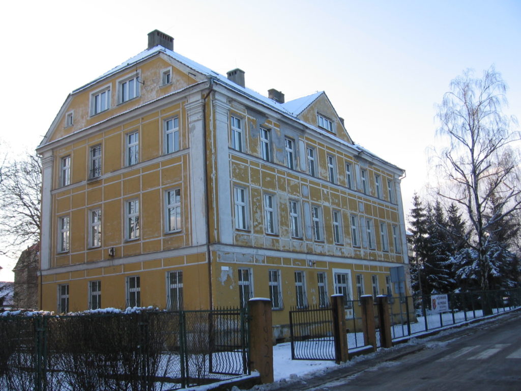 Budynek internatu w Pieszycach. Budynek w kolorze żółtym z ogrodzeniem