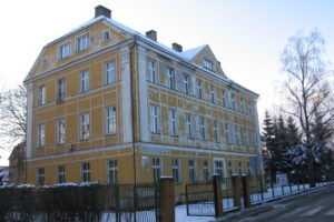 Budynek internatu w Pieszycach. Budynek w kolorze żółtym z ogrodzeniem