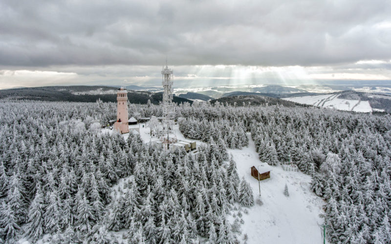 widok z lotu ptaka na zimowy krajobraz gór sowich. w tle wieża widokowa na wielkiej sowie