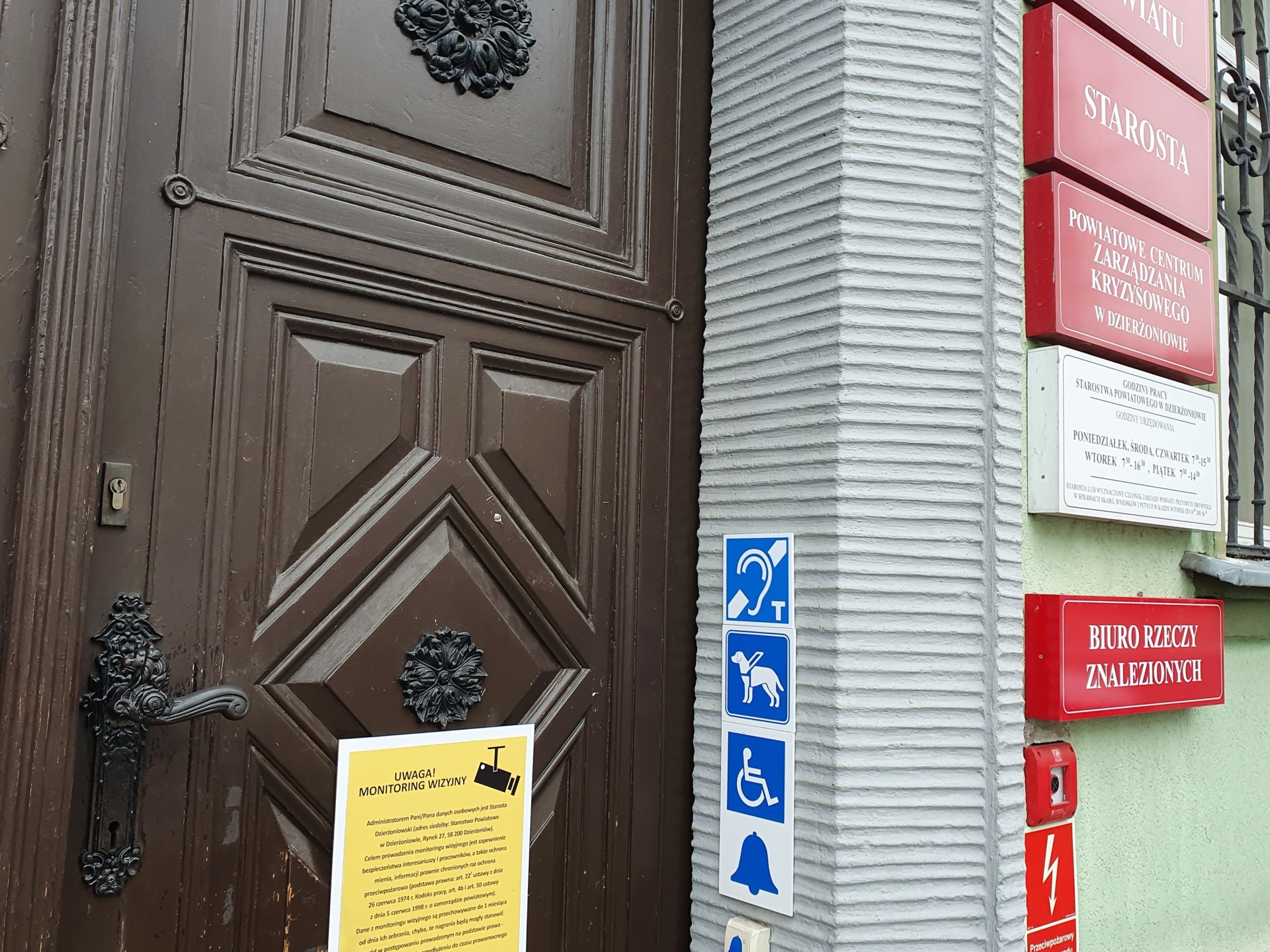Wejście do budynku Starostwa po prawej stronie znak pętli indukcyjnej - na niebieskim tle ucho i duża litera T. 