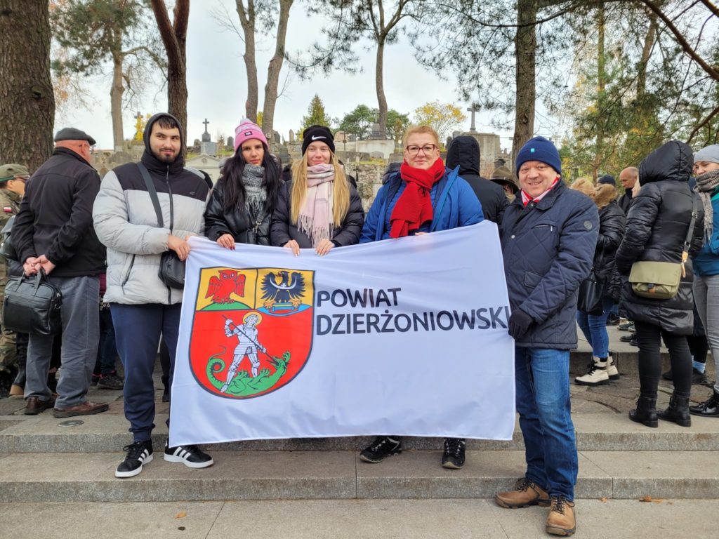 Wolontariusze z opiekunami trzymają flagę z logo Powiatu Dzierżoniowskiego