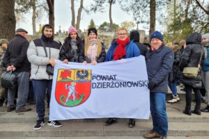 Wolontariusze z opiekunami trzymają flagę z logo Powiatu Dzierżoniowskiego