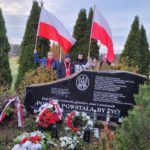 Wolontariusze z flagami Polski na cmentarzu