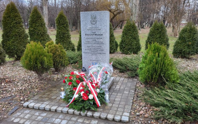 kwiaty i znicze złożone pod pomnikiem