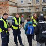 policjanci wraz z przedstawicielem młodzieżowego zespołu rozdający odblaski 4