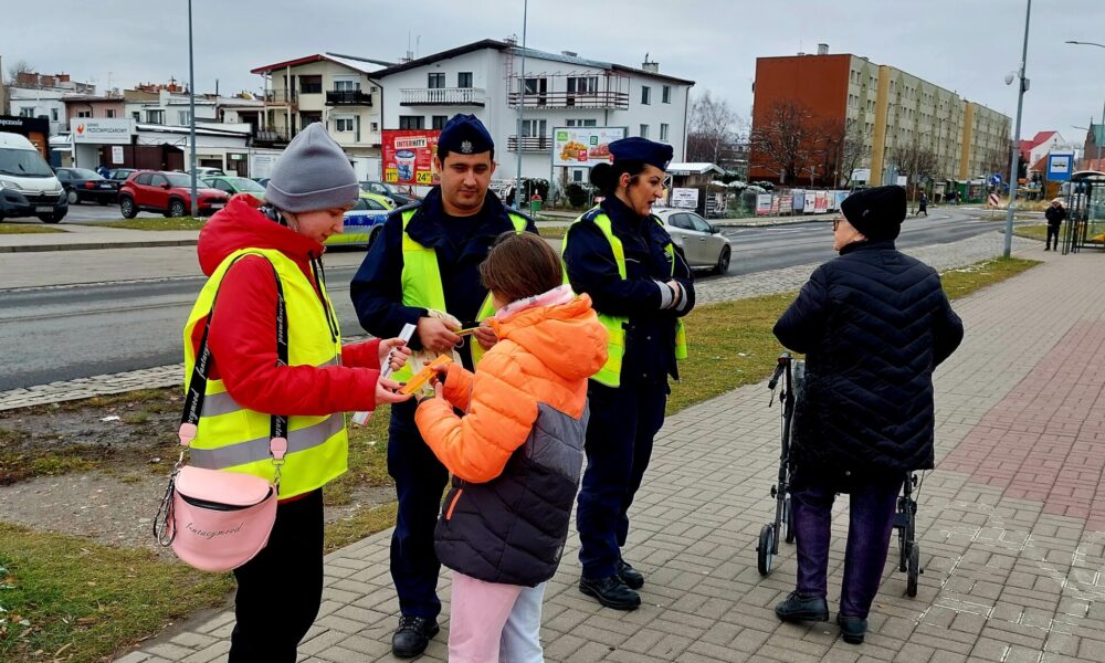 policjanci wraz z przedstawicielem młodzieżowego zespołu rozdający odblaski 3