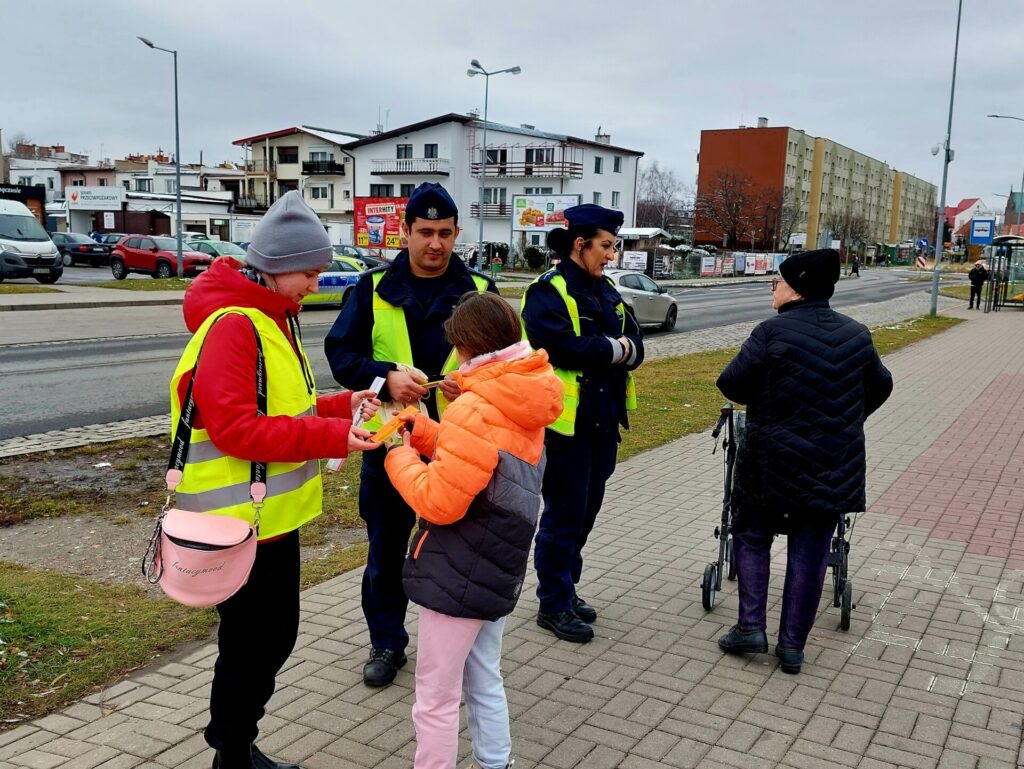 policjanci wraz z przedstawicielem młodzieżowego zespołu rozdający odblaski 3