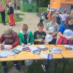 dzieci siedzą przy stoliku i oglądają ulotki