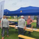 ludzie stoją przy namiocie i rozmaiwają