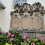Płyta nagrobna rodziny von Falckenhann na ścianie kościoła z zewnątrz, przed nią kwiaty