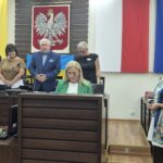 Pani nauczyciel składa ślubowanie, obok stoi dyrektor wydziału edukacji, w tle przewodniczący rady