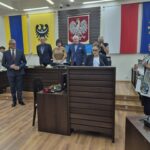 Pani nauczyciel składa ślubowanie, obok stoi dyrektor wydziału edukacji, w tle starosta, przewodniczący rady