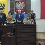 Pani nauczyciel składa, w tle przewodniczący rady