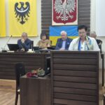 dyrektor wydziału edukacji przemawia, w tle siedzą przewodniczący rady