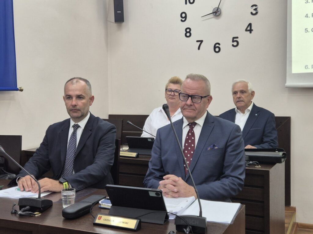 zarząd powiatu, siedzą przy stołach, na ścianie zegar