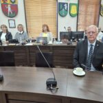 poseł na sejm RP siedzi przy stole, w tle radne