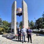 Starosta, Burmistrz Dzierżoniowa i Adam Wolniak na placu przed pomnikiem, w tle pomnik i drzewa