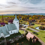 kościół w Dobrocinie z góry, wokół cmentarz i mur, dalej zabudowania wsi, w tle góry.