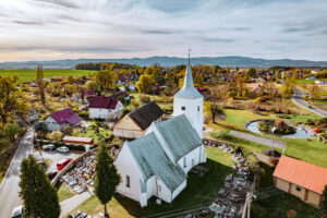 kościół w Dobrocinie z góry, wokół cmentarz i mur, dalej zabudowania wsi, w tle góry.