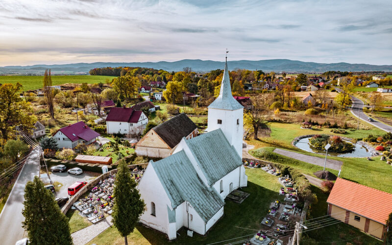 kościół w Dobrocinie z góry, wokół cmentarz i mur, dalej zabudowania wsi, w tle góry.