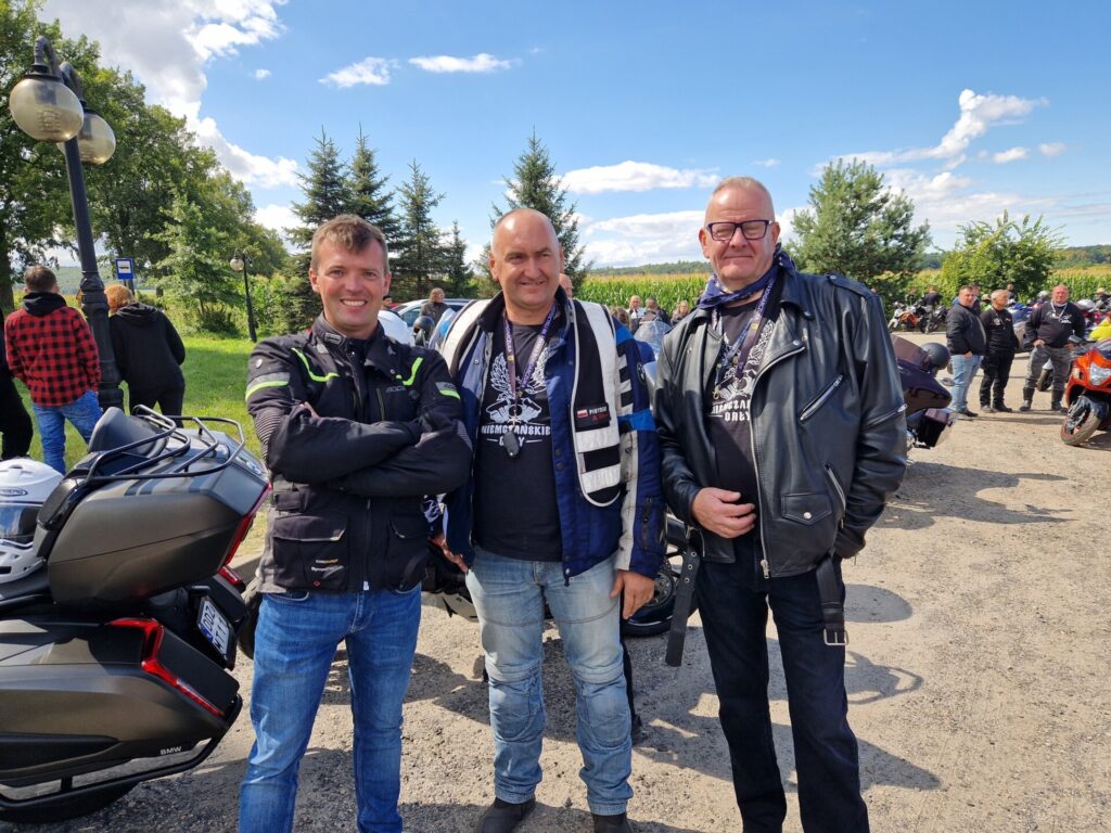 Trzech mężczyzn, w tym starosta, w tle motocykle