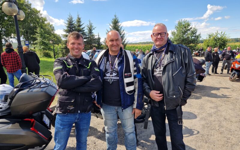 Trzech mężczyzn, w tym starosta, w tle motocykle