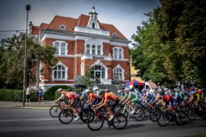 Kolarze jadą ulicą przed budynkiem banku w Dzierżoniowie.