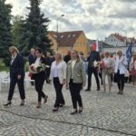ludzie składają kwiaty pod pomnikiem