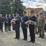 przedstawiciele służb mundurowych stoją z kwiatami