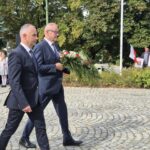 starosta i wicestarosta idą z kwiatami pod pomnik