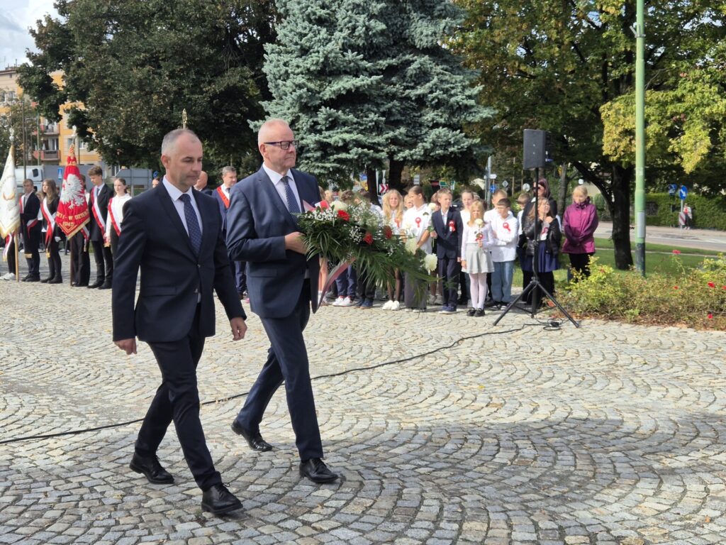 starosta i wicestarosta idą z kwiatami pod pomnik