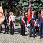 poczty sztandarowe i uczniowie stoją na placu