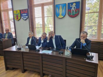 mężczyźni siedzą przy stole na sali sesyjnej