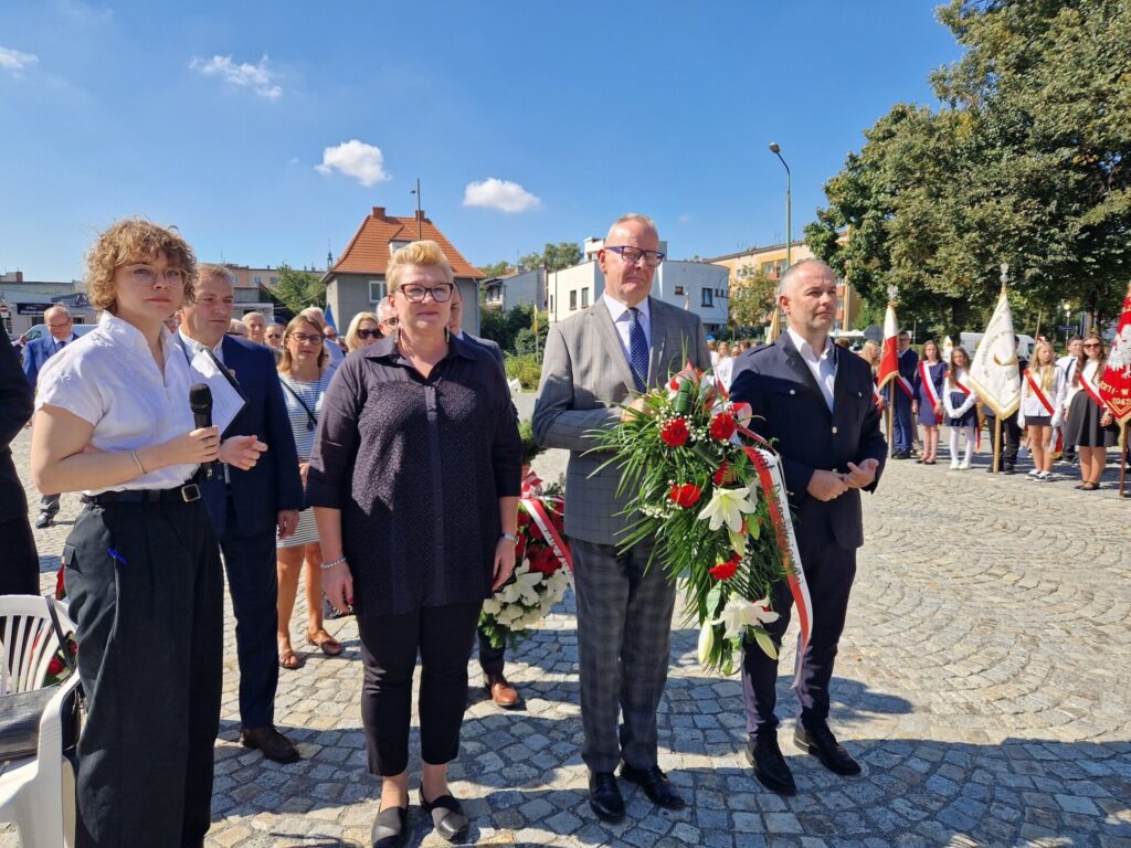 przedstawiciele Zarządu Powiatu z kwiatami, za nimi pozostali uczestnicy obchodów
