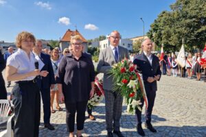 przedstawiciele Zarządu Powiatu z kwiatami, za nimi pozostali uczestnicy obchodów