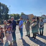 ludzie stoją i czekają na złożenie kwiatów pod pomnikiem