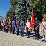 na placu stoją poczty sztandarowe, w tle drzewa