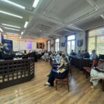 uczestnicy szkolenia siedzą przy stołach i słuchają