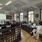 uczestnicy szkolenia siedzą przy stołach i słuchają