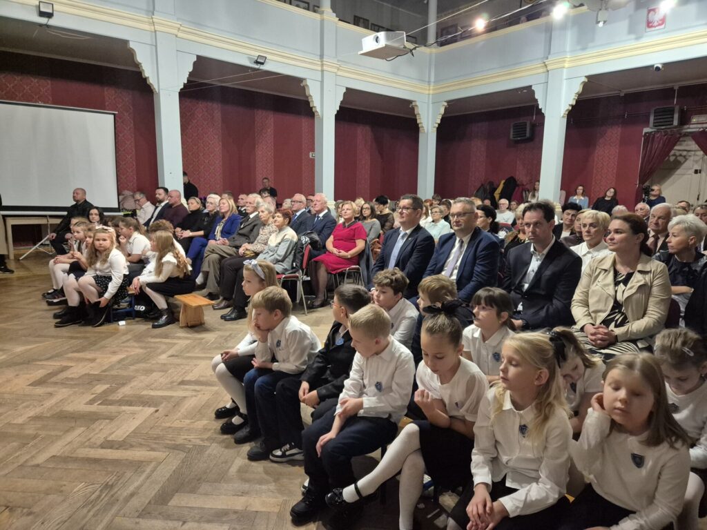 ludzie siedzą na krzesłach, z przodu dzieci