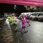 kobiety na rolkach dojeżdżają do mety, w tle strój dinozaura