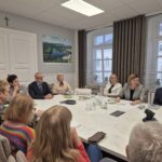 ludzie siedzą przy stole, widok na starostę