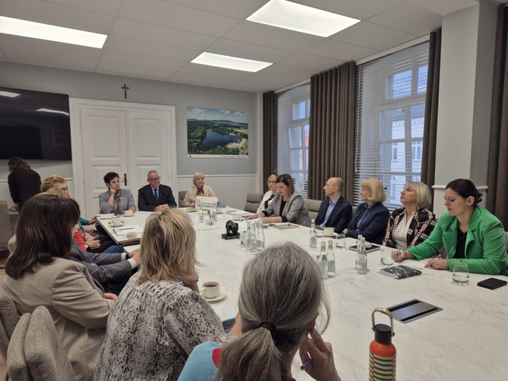 ludzie siedzą przy stole, widok na starostę