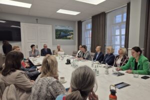 ludzie siedzą przy stole, widok na starostę