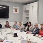 ludzie siedzą przy stole, z tyłu telewizor