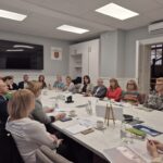 ludzie siedzą przy stole, widok na starostę