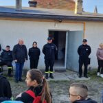 grupa ludzi stoi na placu przed budynkiem