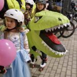 dziewczynka w niebieskiej sukience, za nią instruktor w stroju dinozaura