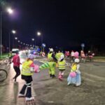 widok z boku na uczestników jadących na rolkach w odblaskowych kamizelkach