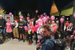 ludzie z różowymi balonami stoją, niektórzy w przebraniach